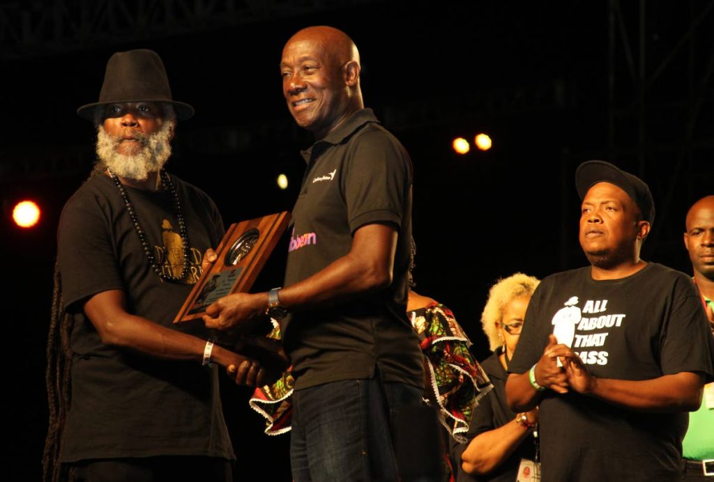 Prime Minister Dr Keith Rowley presents award to Sharlan Bailey, son of the late Winston “Shadow” Bailey in honour of Shadow’s contribution to local culture and calypso at Panorama on Saturday night at the Queen’s Park Savannah. PHOTO BY ROGER JACOB