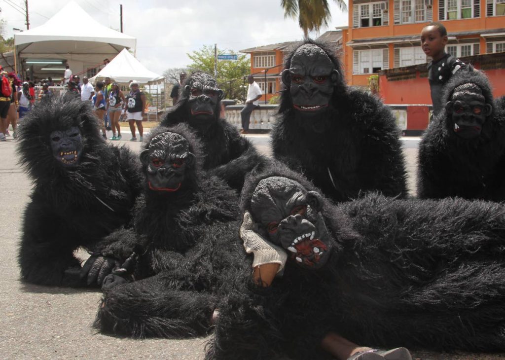 A boy looks curiously at a band of gorillas lying around on Piccadilly Street, Port of Spain on Carnival Tuesday. Piccadilly Street, central to the city's cultural history, and environs will undergo an upgrade. PHOTO BY ROGER JACOB
