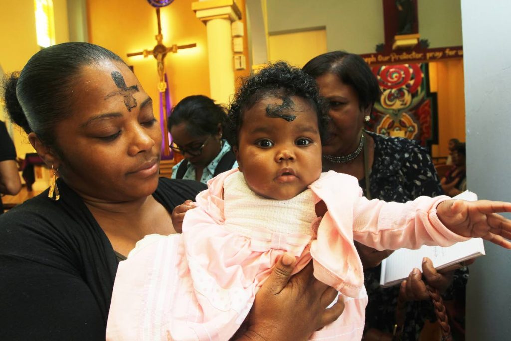 Parishioner Anika Noeriga and her daughter, Ty-Liyah Matiste after receiving ashes at Our Lady of Perpetual Help church yesterday. Archbishop Charles Gordon officiated over yesterday’s mass. PHOTO  BY LINCOLN HOLDER
