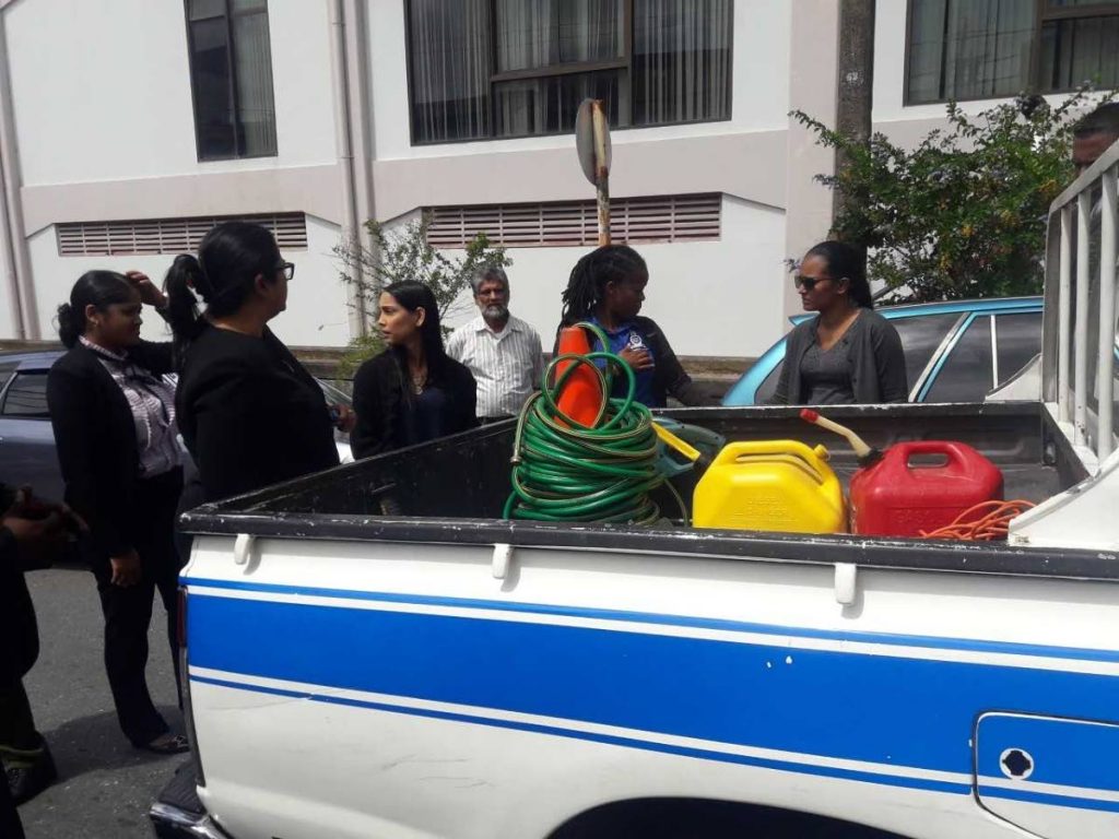 Accused Stephanie Ramdhanie, 27, (extreme right) is accompanied outside San Fernando High Court where senior magistrate Alicia Chankar examined some items for which she is charged with stealing