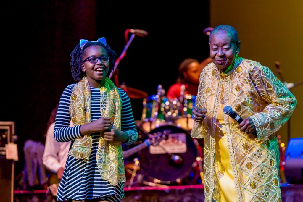 Calypso Rose, right, crowns this youngster a princess as she adorns her with a scarf during her Forever Young concert last Thursday evening at Shaw Park Cultural Complex. PHOTO BY DAVID REID 