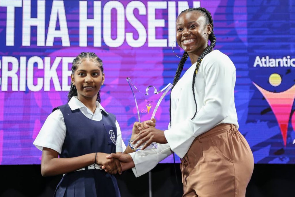 National track star Khalifa St Fort presents the Female Youth Champion of the Year award to Samantha Hosein, of San Francique Presbyterian School during the Atlantanic YES awards,held at the Hilton Trinidad,yesterday.