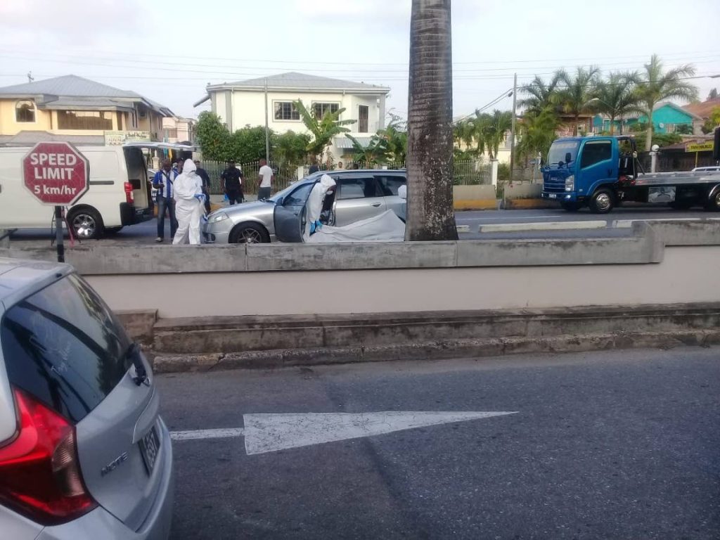 Crime scene investigators look for evidence after Chaguanas pensioner Joseph Phillip was shot in the front seat of a taxi at Gulf City Mall, La Romaine, yesterday