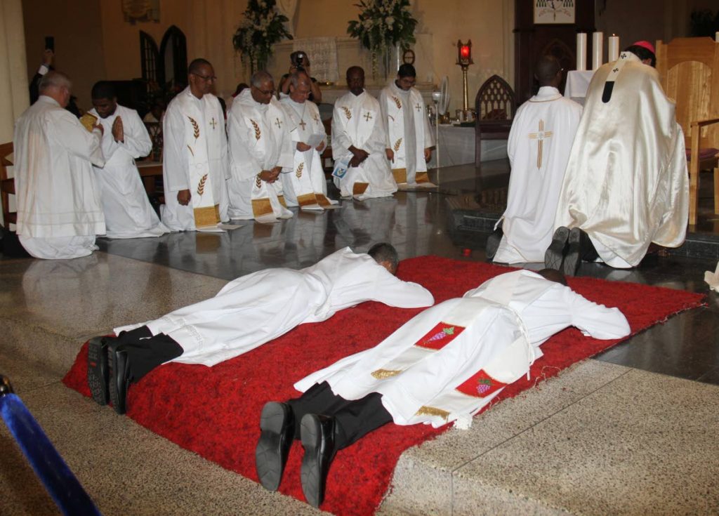 SHOW OF FAITH: New priests Lindsay John, left, and Jeffrey Supersad lie flat on the ground
 during their ordination ceremony on Monday evening at the Cathedral of the Immaculate 
Conception in Port of Spain. PHOTO BY ANGELO MARCELLE