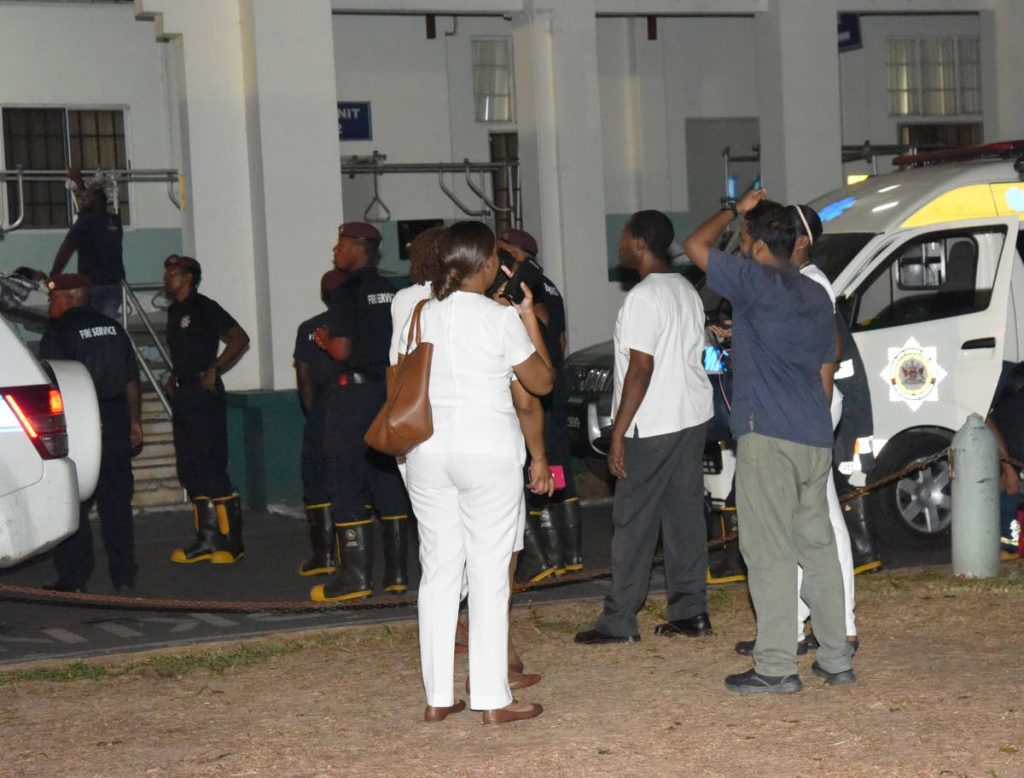 Nurses and Doctors stand outside during a fire at the Port of Spain General Hospital last night. PHOTO BY KERWIN PIERRE