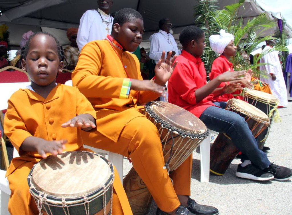 A young drummer in deep concentration during a performance with older children at Spiritual Shouter Baptist Liberation Day celebrations, Eddie Hart Grounds, Tacarigua.