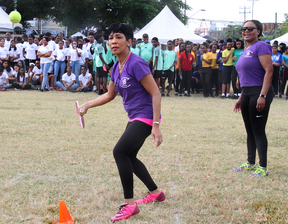 Sharon Rowley, wife of Prime Minister Dr Keith Rowley, attempts to hit a ball during a game of rounders during the Students’ Fitness Fair 2019 held at the Nelson Mandela Park recently. Looking on is Minister of Sport and Youth Affairs Shamfa Cudjoe. PHOTO BY AYANNA KINSALE
