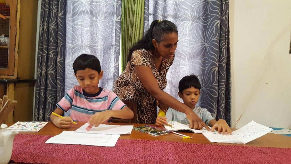 Halena Kong Ting explains a point to her son Zachary, nine, while his brother, Rafael, seven, does some school work at home. 