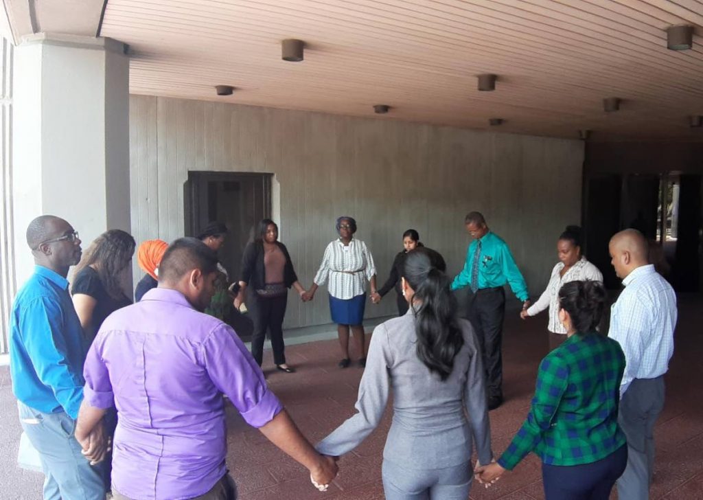 Judiciary workers pray in front of the Hall of Justice in Port of Spain, yesterday. 