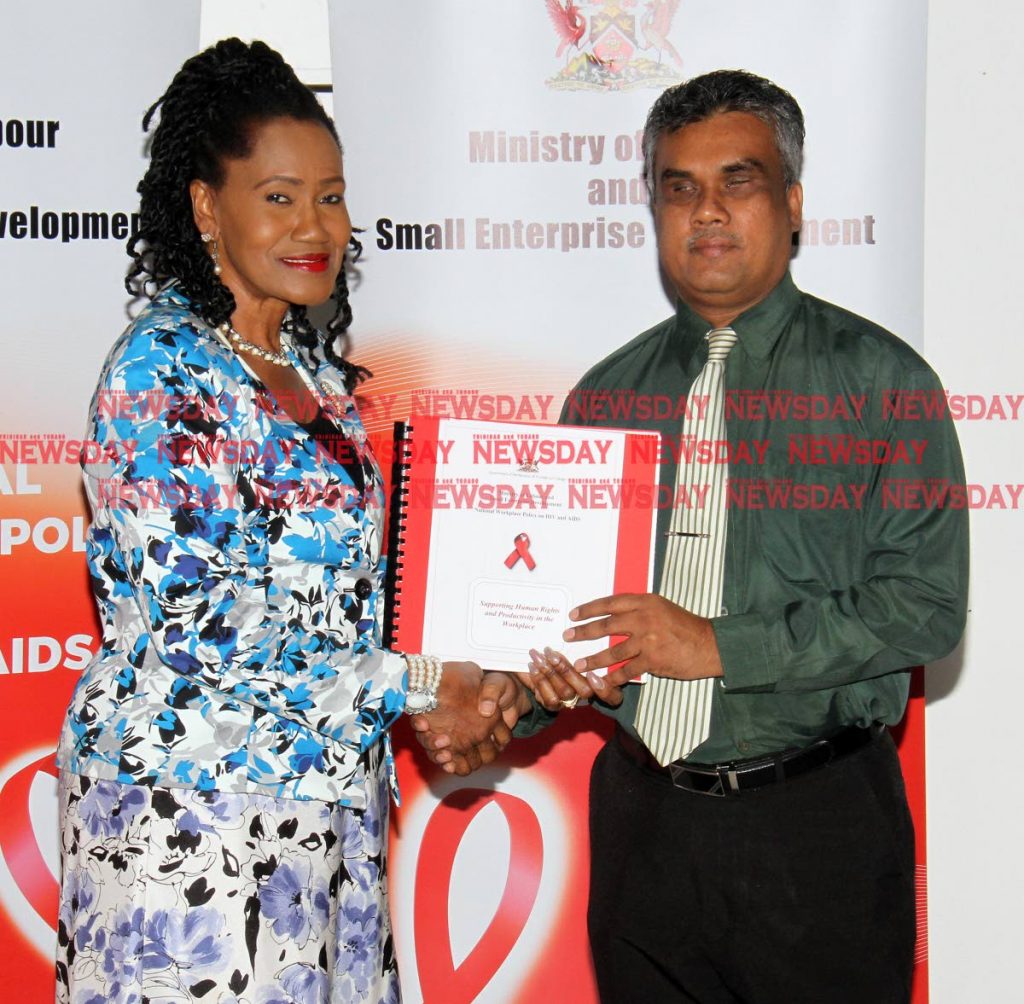 Labour and Small Enterprise Development Minister Jennifer Baptiste-Primus hands over copies of the National Workplace Policy on HIV and Aids, and an employee brochure document in braille, to Kenneth Surratt, executive officer of the Blind Welfare Association at the National Library, Port of Spain on Friday. PHOTO BY ANGELO MARCELLE
