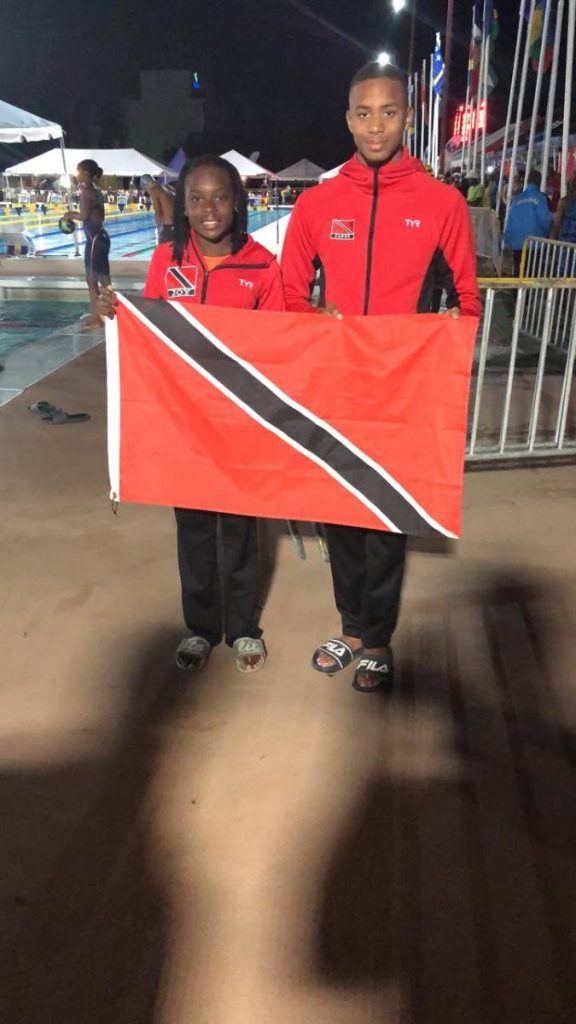 TT Carifta gold medallists Zarek WIlson, right, and Joy Blackett, with the national flag in Barbados. PHOTO BY SHERDON PIERRE 