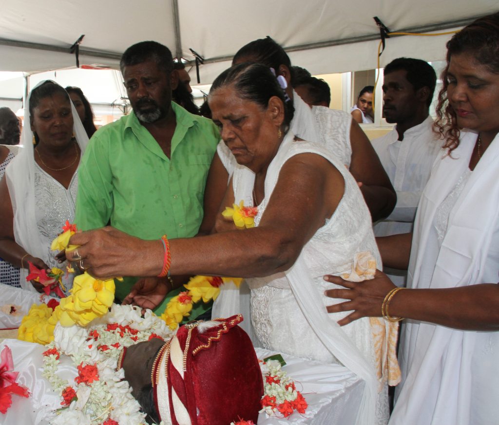 Etwarie Gyandass mother of dead fisherman Chunilal Gyandass 53, placed a mala of flowers on his chest as he lay in the coffin during the funeral at Bucarro Road , Freeport  home.

Photo: Vashti Singh