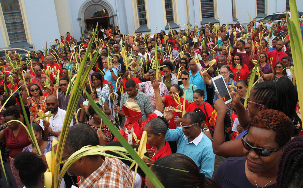 HOLY WEEK BEGINS: Archbishop Jason Gordon sprinkles holy water on the congregation at the Our Lady of Perpetual Help RC Church in San Fernando during Palm Sunday mass yesterday.   PHOTO BY VASHTI SINGH