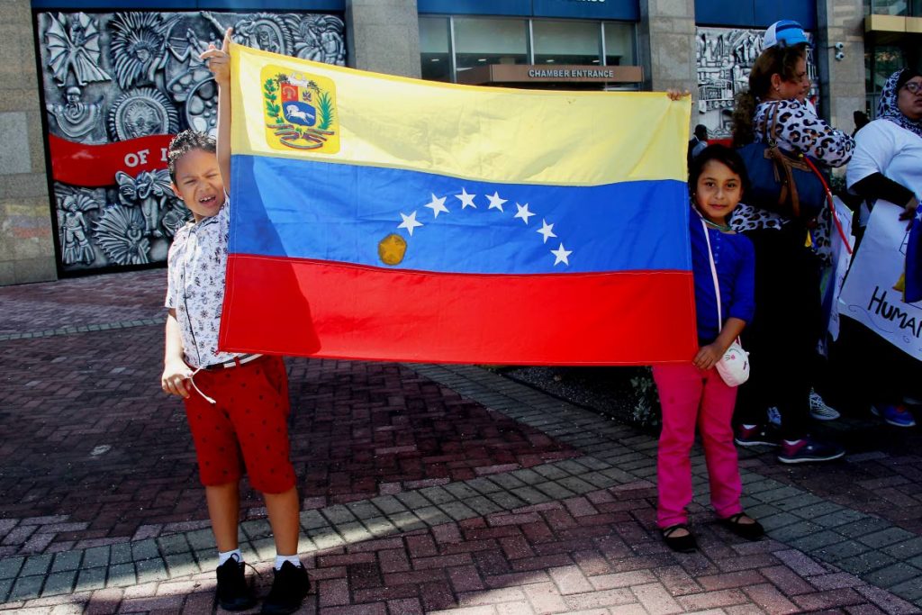 Antonella Abreu-Valdez and her brother Carlos hold up the national flag of Venezuela outside the Parliament in Port of Spain during a protest by Venezuelans living in TT on January 26. PHOTO BY ROGER JACOB