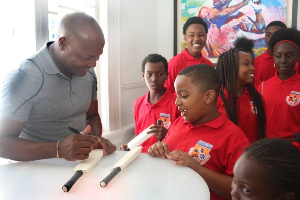 In this 2017 file photo, Brian Lara signs miniature bats for members of the St James Police Youth Club. 