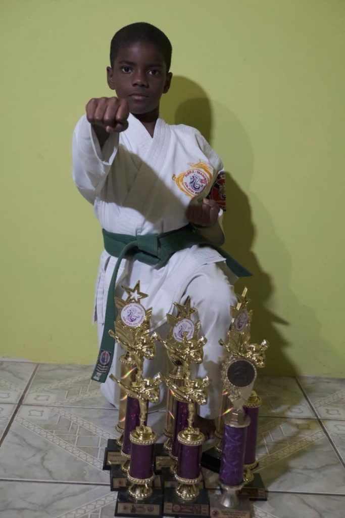 Nine-year-old Xzavier King poses with trophies he won at past competitions.