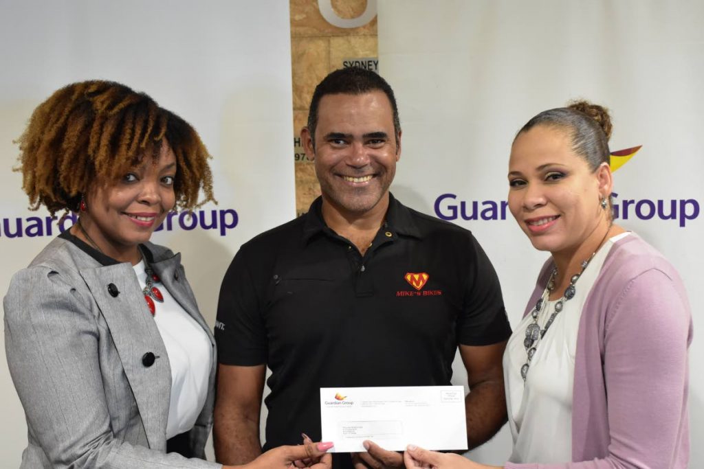 Michael Phillips (centre) of Phillips Promotions receives a cheque from  Ayesha Boucaud-Claxton (right), Senior Manager, Group Corporate Communications and Kele Ransome, Corporate Communication Officer- CSR & Event of Guardian Group.