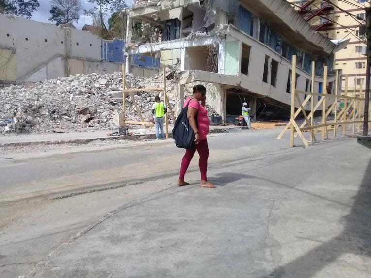 A resident of east Port of Spain crosses Picadilly Street near the old Besson Street Police Station, where workmen are building fences to contain demolition works. 