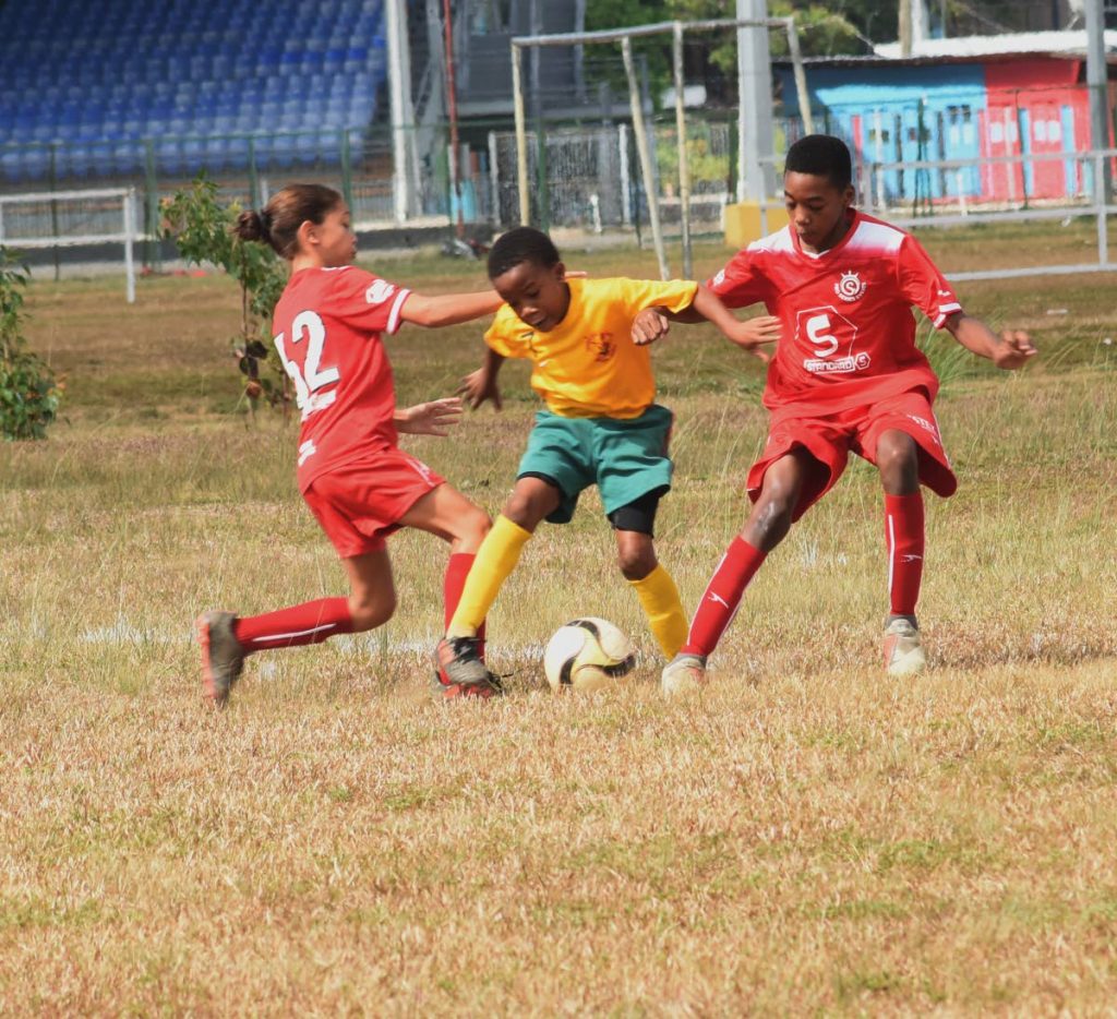 Jahseem Celestine of Trendsetter Hawks, centre, slips between Proseres' Kaitlyn Darwent, left, and Jonathan Mason in the Under 11 division of the Republic National Youth League. PHOTO BY KERWIN PIERRE 