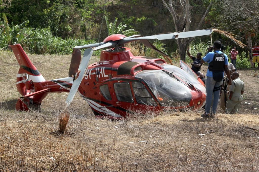 Occupants are removed from a National Helicopter Services Ltd helicopter after it crashed Windy Hill, La Resource North off the Arima Old Road, in Arouca, during a search for escaped prisoners on May 18, 2019. 