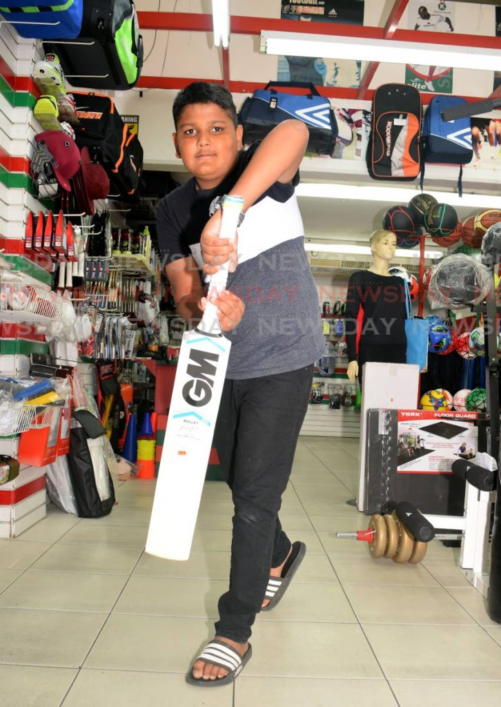 Aidan Mamchan tests out a bat at a sports store. PHOTOS BY VIDYA THURAB