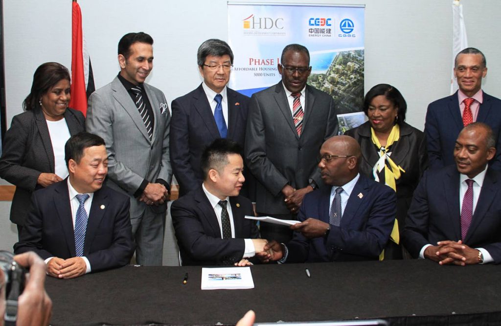 Executive vice president of CGGC Energy China Zhou Xing (Larry), centre, and HDC chairman Newman George shake hands after signing documents for a housing construction project at the HYATT Regency, Port-of-Spain yesterday. Looking on are, from left, CGGC president Liu Huailiang, HDC managing director Brent Lyons, Minister of Trade Paula Gopee-Scoon, back from left, Attorney General Faris Al-Rawi, China’s ambassador to TT Song Yumin, Minister of Housing Edmund Dillon, Minister in the Ministry of Public Administration Marlene McDonald and Minister of Foreign Affairs Dennis Moses.