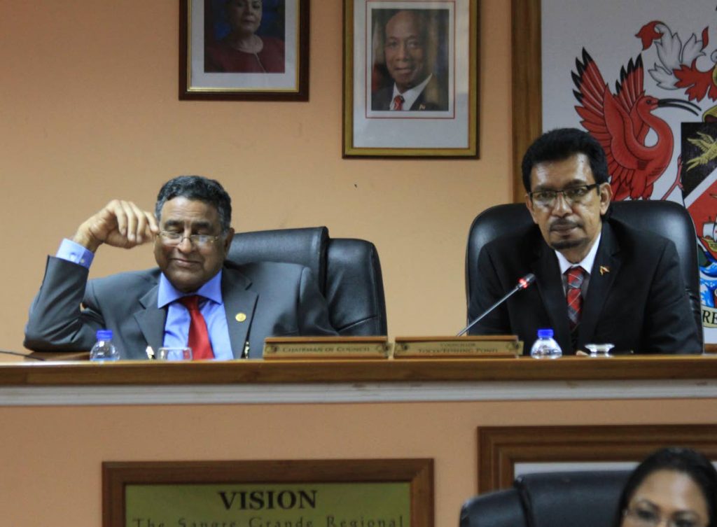 Chairman of the Sangre Grande Regional  Corporation Terry Rondon, left, listens as Minister of Rural Development and Local Government Kazim Hosein, right, speaks at the corporation's statutory meeting. 
