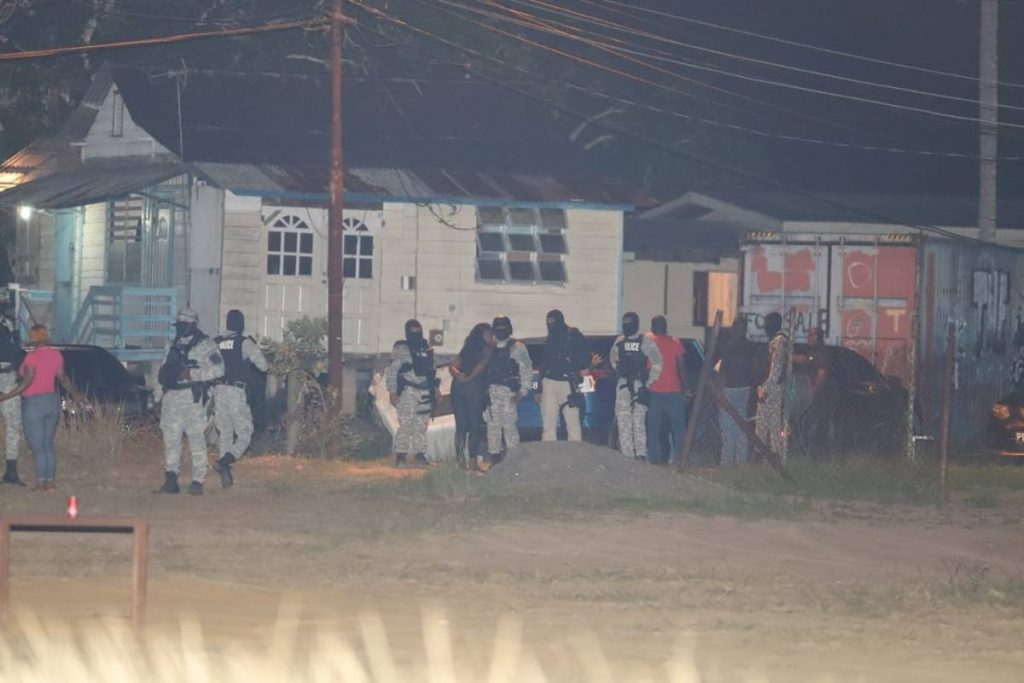 Police and residents at Ralph Narine Trace, South Oropouche where escapees Michael Findley and Olatunji Denbow were captured on Saturday. PHOTO BY JEFF MAYERS