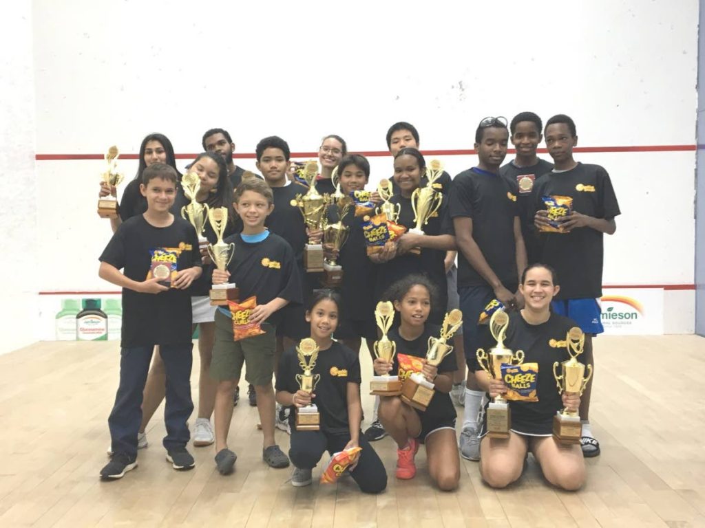 The winners of the junior squash tournament pose with their trophies.