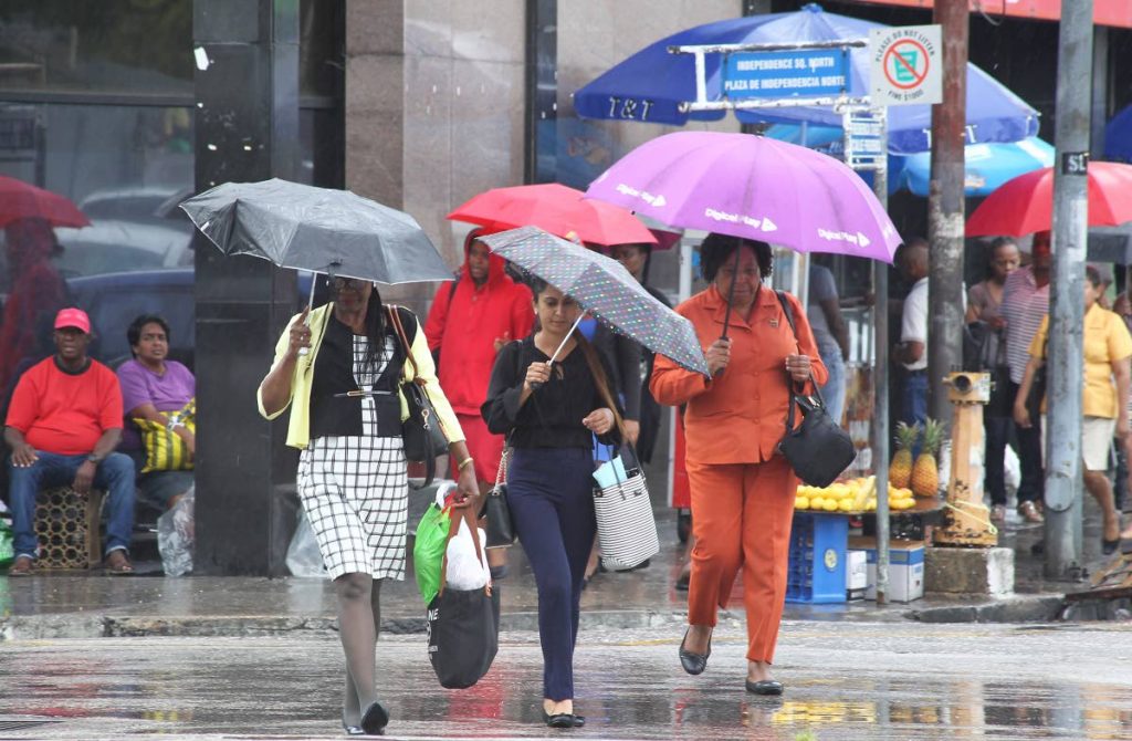 File photo: Pedestrians with their trusty umbrellas walk through rain along Independence Square in Port of Spain. 