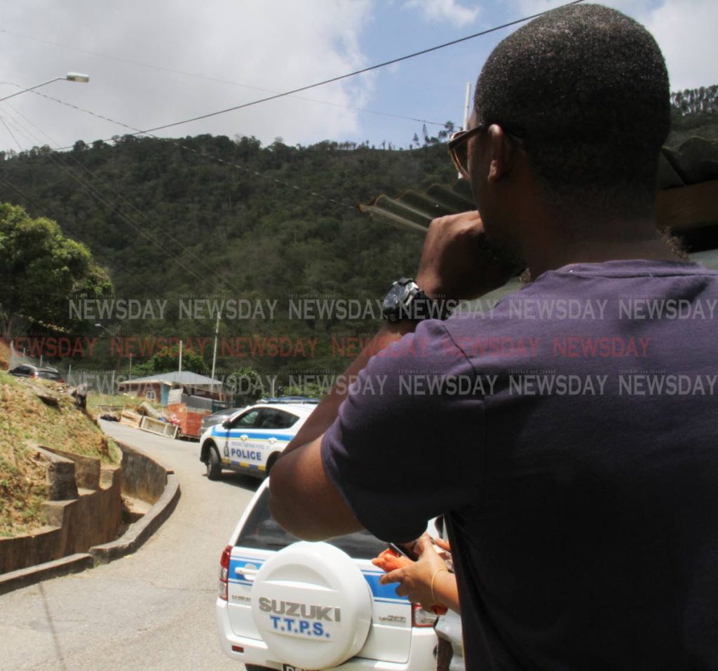 Residents look on at the body of Christopher Jones 29, in the distance, who was shot and killed at Wharf Trace, Maracas, St Joseph, on Thursday morning. PHOTO BY ANGELO M MARCELLE