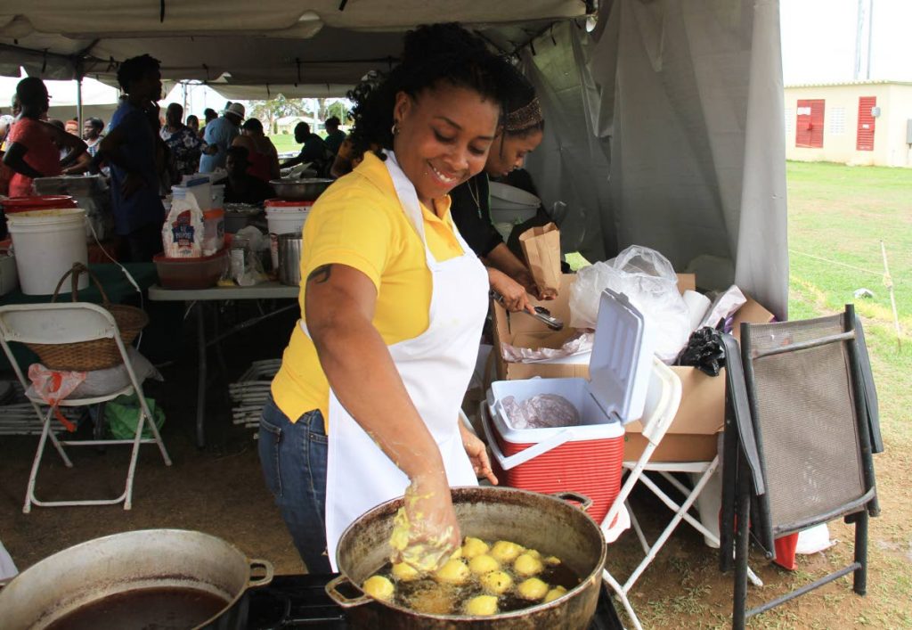 Keisha Boyce makes a tasty mango pholourie at the Mango Melee festival yesterday at Eddie Hart grounds in Tacarigua. 
