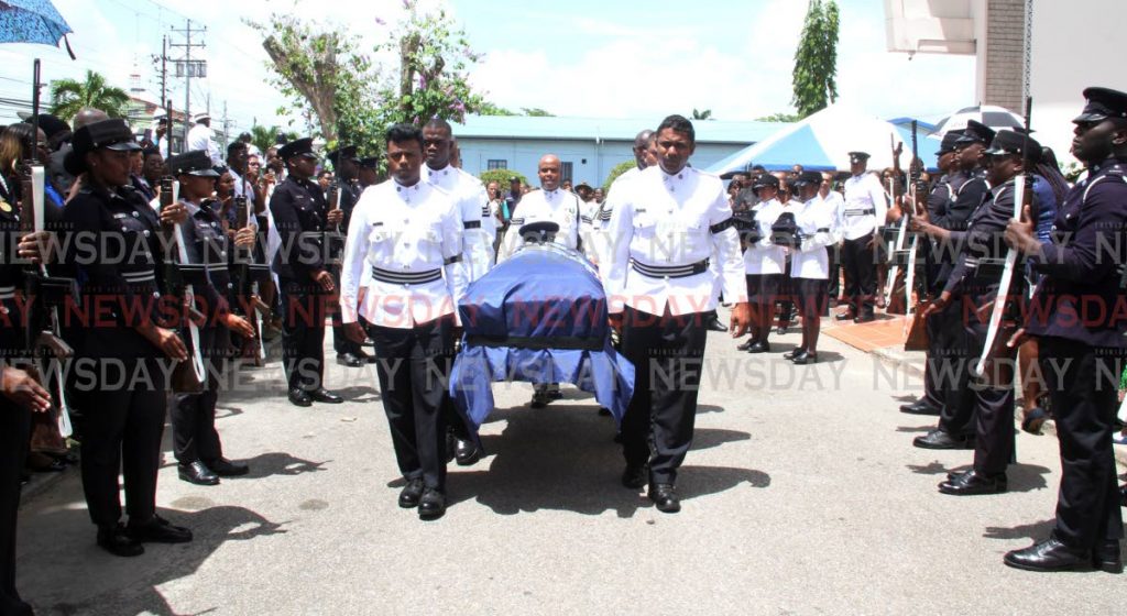 PC Dexter Theophille is saluted by members of the police service as his body is taken into the St Paul's RC Church in Couva for his funeral on Thursday. PHOTO BY VASHTI SINGH