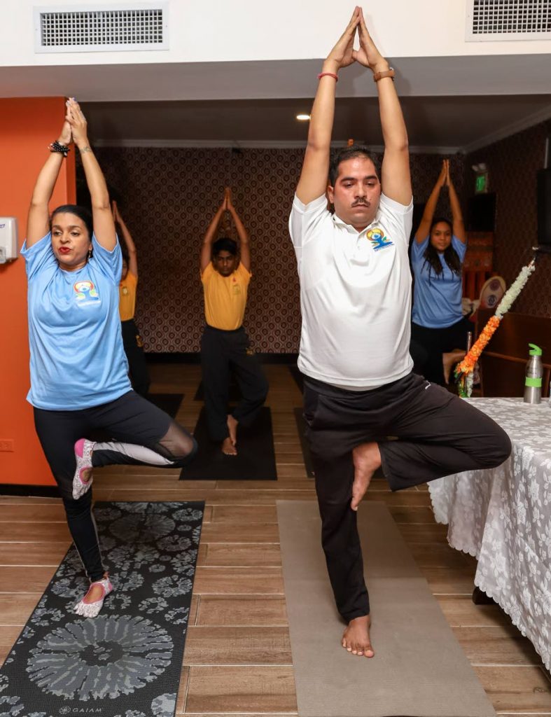 STRETCH:  Simone Kissoon, owner of The Bodhi Tree yoga and health studio, and Omprakash Kuriyal, yoga teacher from the Indian High Commission lead a yoga demonstration alongside students of Ghandi Memorial Vedic School on Thursday. 