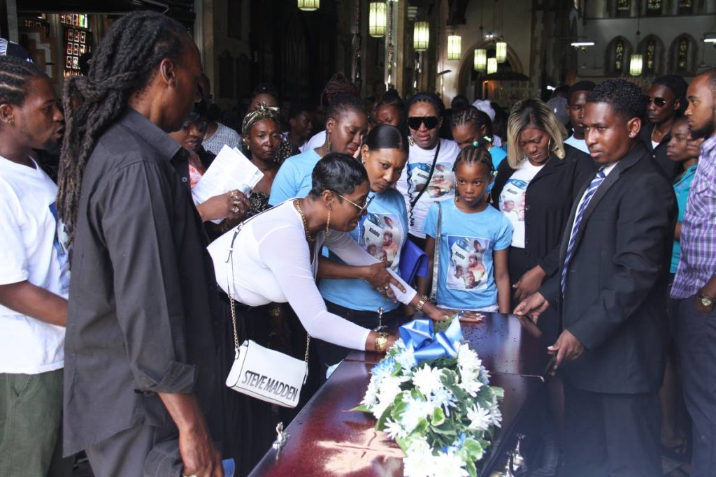 SORROW: Kimette Johnson, left, touches the casket of her son Kadeem during his funeral yesterday at the Holy Trinity Cathedral in Port of Spain. PHOTO BY AYANNA KINSALE