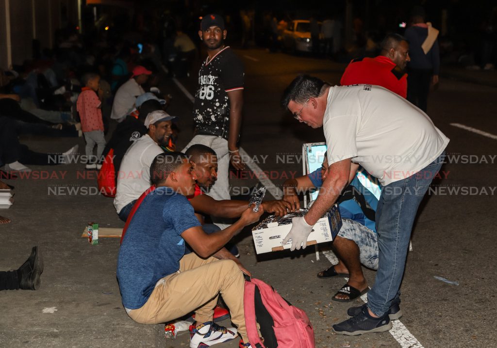 Artist Peter Sheppard distributing food to Venezuelans outside the Queen's Park Oval registration centre last night.

Photos: Jeff K Mayers