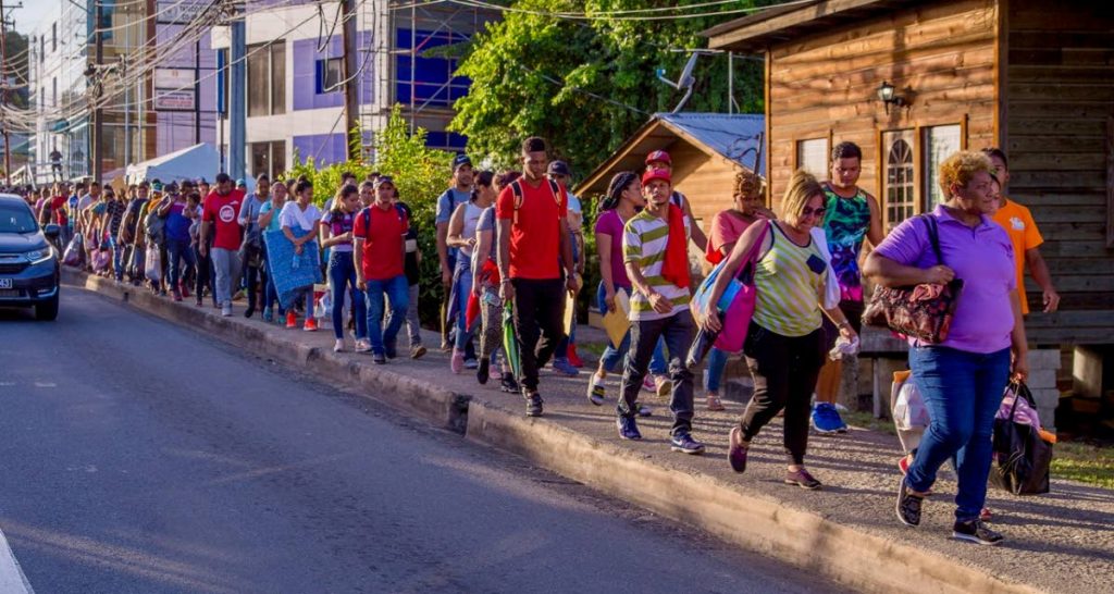 Scores of Venezuelans are escorted through Scarborough to Port Mall on Friday afternoon after they were turned away at the Caroline Building although they were in line at 5 pm, the deadline for registration. National Security Minister Stuart Young says this was unauthorised and ordered the Venezuelans be registered in Tobago today. PHOTO BY DAVID REID