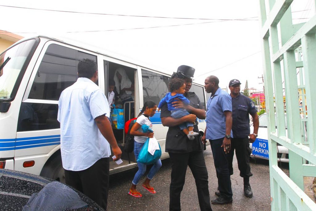 OUT OF TIME: Several Venezuelans, including a baby in a policewoman’s arms, were taken to the Immigration Department in San Fernando yesterday after they were found to have illegally entered the country. 