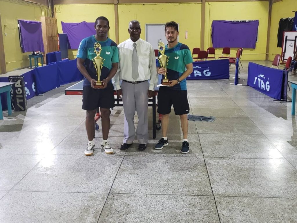 Curtis Humphreys,left, and Kenneth Parmanand,right display their awards after claiming the top prizes, at the WASA Tag Team table tennis tournament, on Sunday, at the WASA grounds, St Joseph. At centre, is former coach Roland Charles.