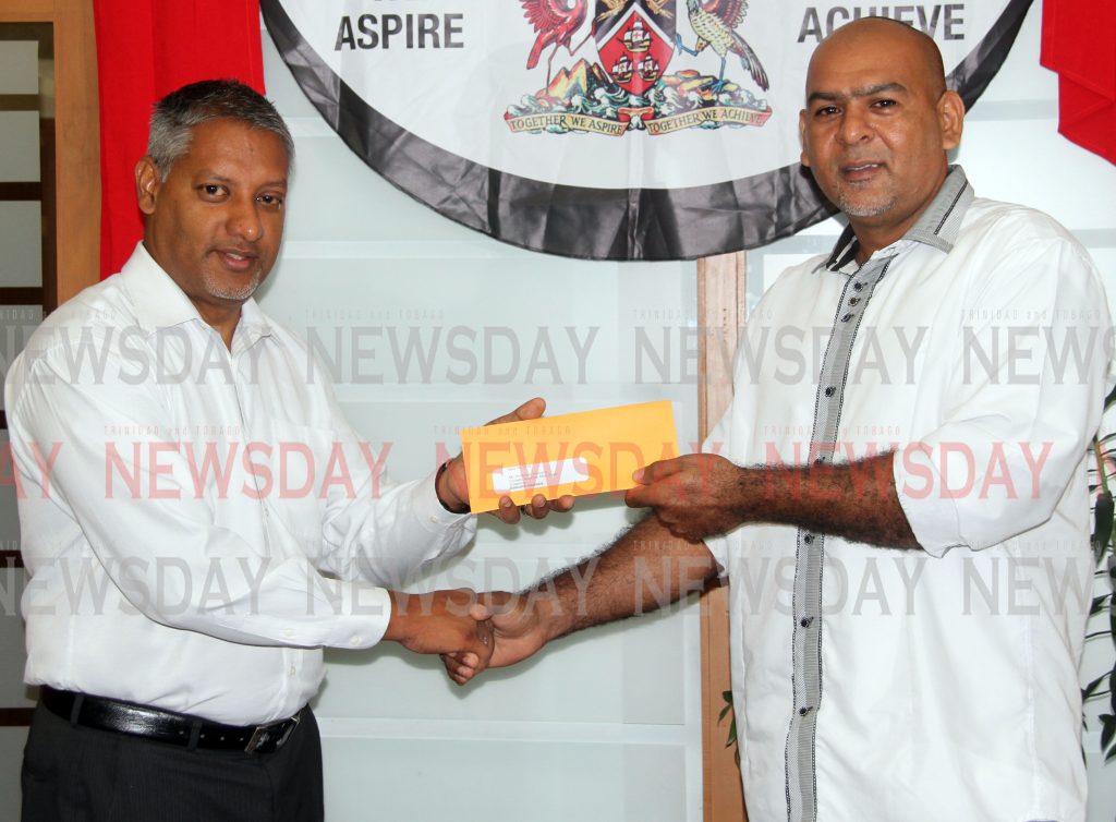 Agriculture Minister Clarence Rambharath, left, presents farmer Anderson Salzano with his land lease during a ceremony at the ministry in Charlieville last Wednesday. 

Photo: Vashti Singh