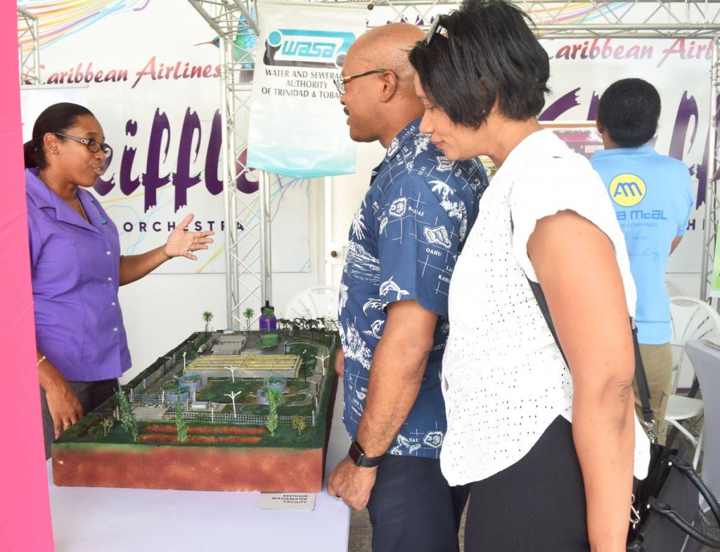 A representative from WASA uses a model of the Beetham wastewater treatment plant to explain to members of the public the workings of the plant, at the IDB's Cheer Fair held at the CAL Skiffle steel orchestra's panyard, Coffee St, San Fernando. - File photo by Vidya Thurab