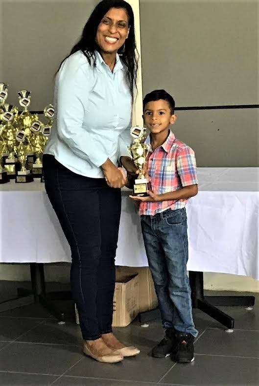 Under-10 division winner, Kyan Muradali, received a trophy from TT Chess Association president Sonja Johnson, when the Kings & Queens Chess Club of Arima hosted its inaugural Open Rapid Play event atthe  UTT O’s Meara Campus, Arima, on Saturday. 
