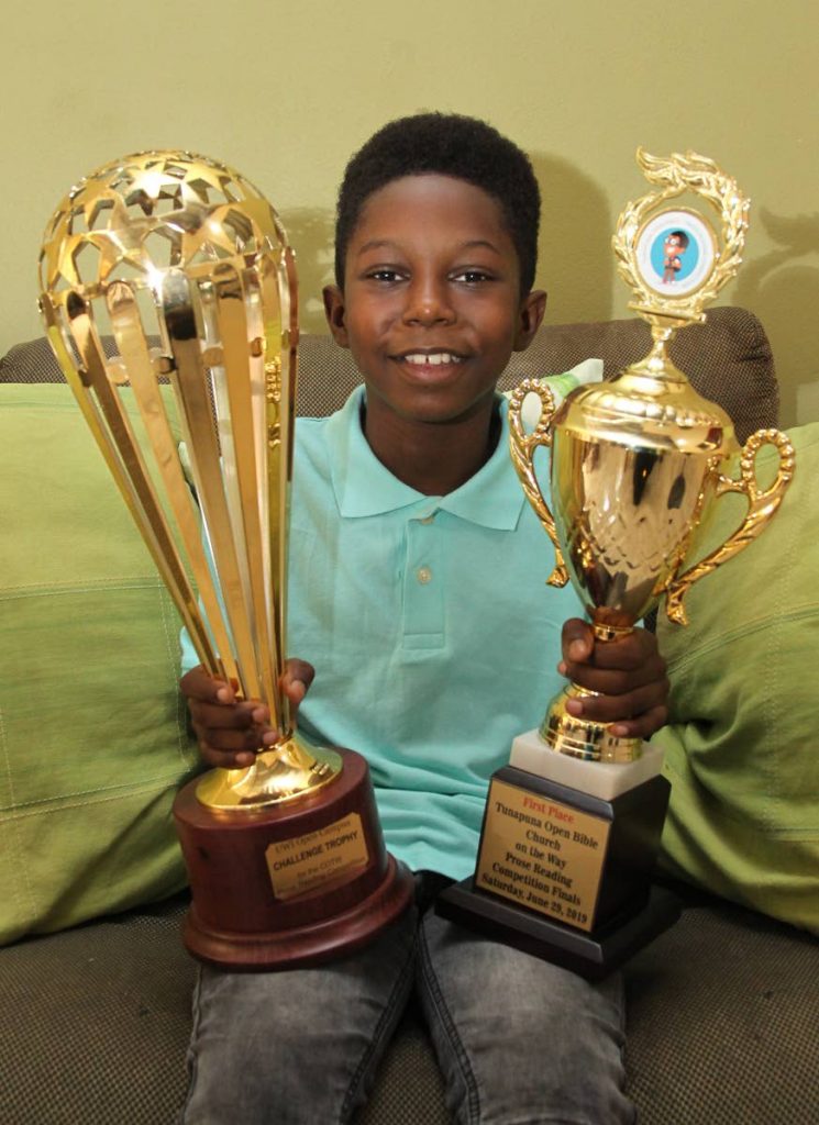 Jaylun Goodridge proudly displays his trophies as the winner of the 2019 prose reading competition. The competition for standard four schoolboys was hosted by the Tunapuna Open Bible Church of the Way on June 29.  PHOTO BY ROGER JACOB
