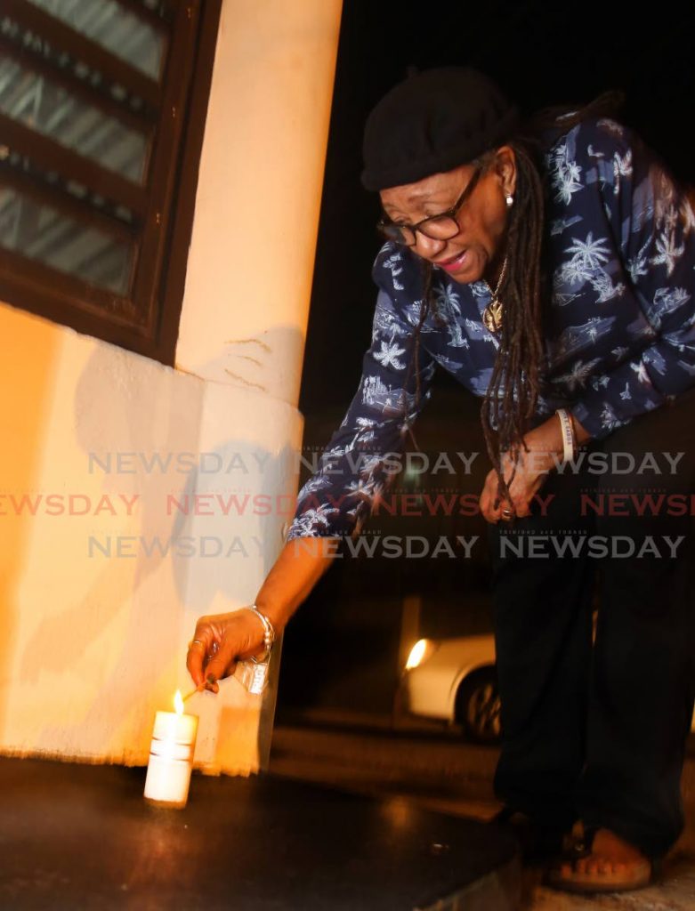 Songstress Mavis John lighs a candle outside the Little Carib Theatre in Woodbrook in memory of slain actor/director Raymond Choo Kong on Monday. PHOTO SUREASH CHOLAI