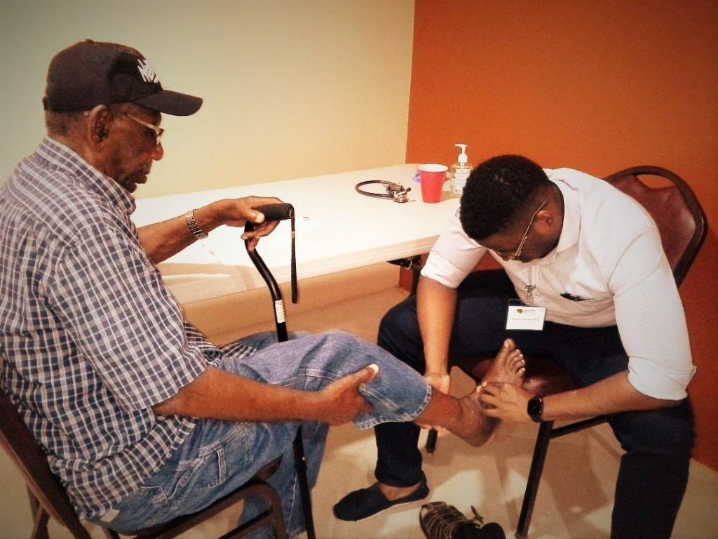 A member of the community gets his feet checked by Dr Mikhail Carlow at the Adult Day Centre health fair in Bon Accord.