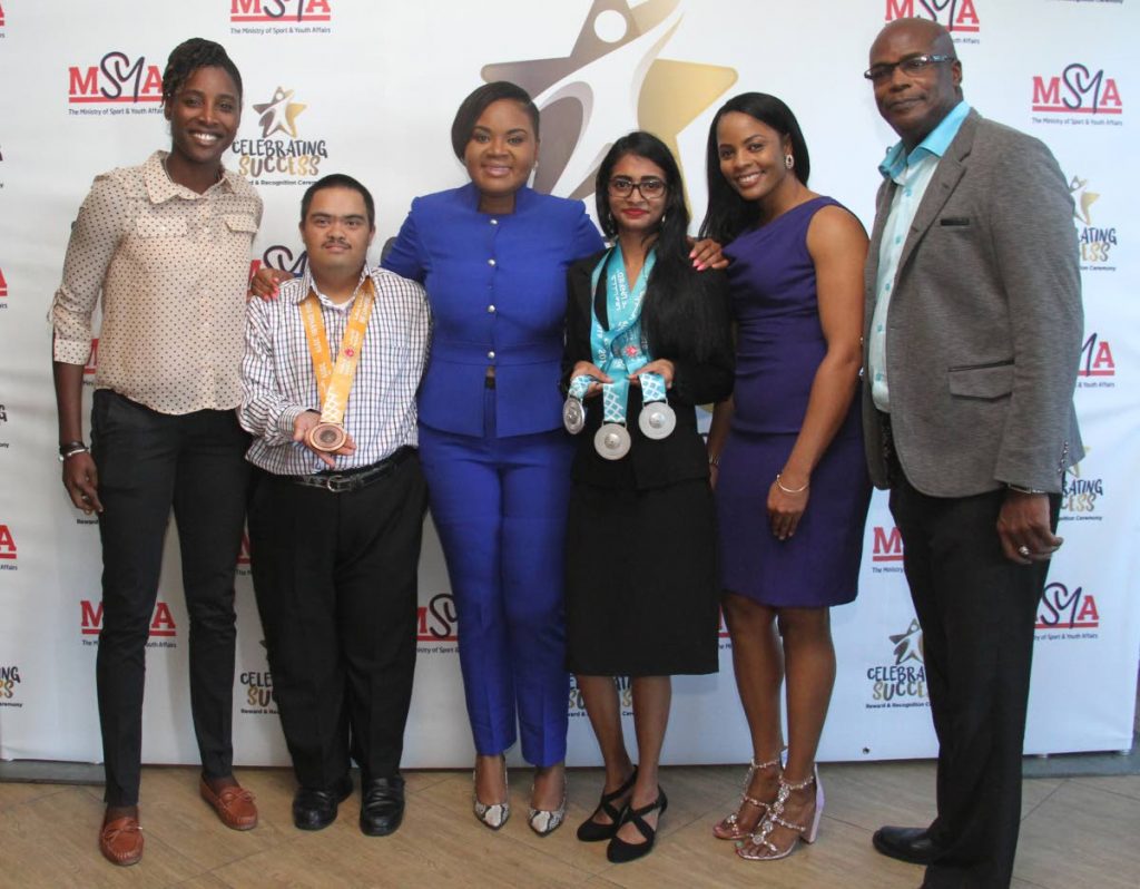 Minister of Sport and Youth Affairs Shamfa Cudjoe, third from left, takes a photo with cricketer Britney Cooper, from left, bocce players Bernard Singh and Alicia Khan, cricketer Merissa Aguilleira and TT’s first Olympic gold medallist Hasely Crawford at the Rewards, Recognition and Cheque Presentation Ceremony at the National Racquet Centre, Tacarigua, yesterday. 