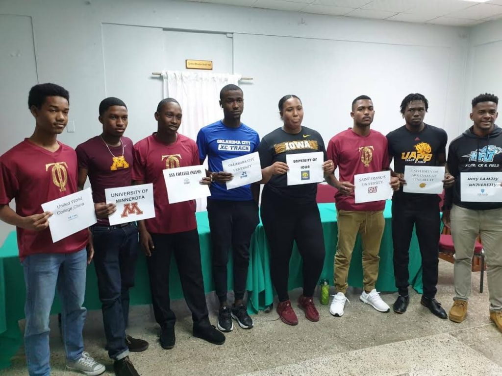 Memphis Pioneers’s track and field athletes, who earned scholarships through the club hold cards bearing the names of the colleges they will attend at a ceremony hosted by the club  in Woodbrook, yesterday. 