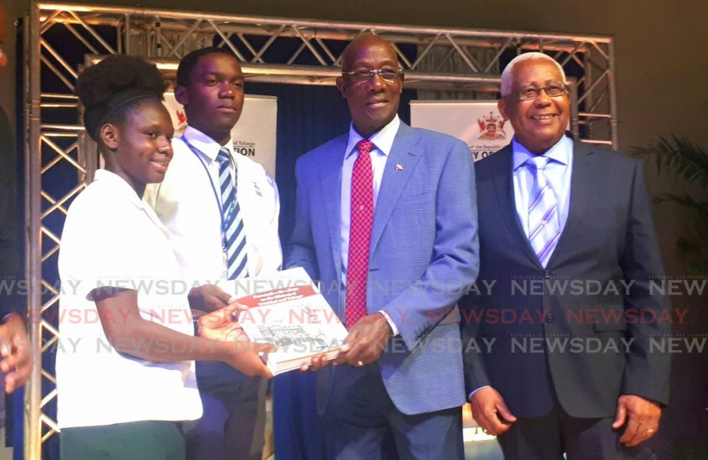 Students present a copy of Foundation readings on the history of TT to Prime Minister Dr Keith Rowley at the book launch held at the Government Campus Plaza Auditorium, Wrightson Road, Port of Space. Right, Minister of Education Anthony Garcia.