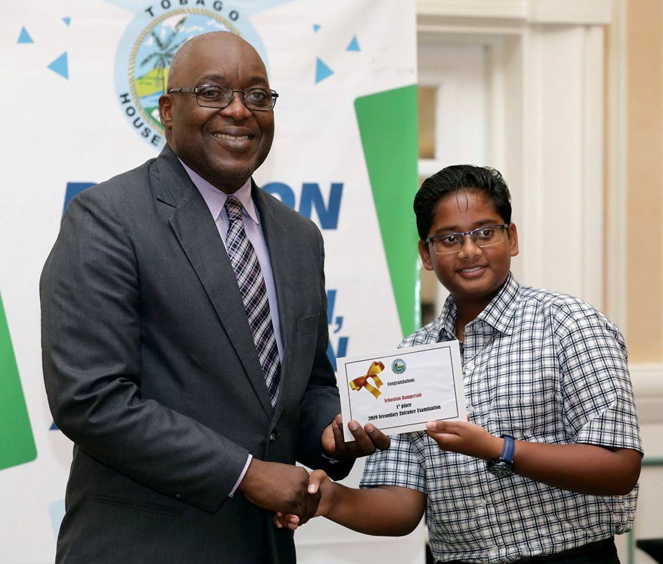 Chief Secretary Kelvin Charles, left, presents former Buccoo Government Primary School student and Tobago’s top SEA student Sebastian Rampersad with a cheque, earlier this year. 