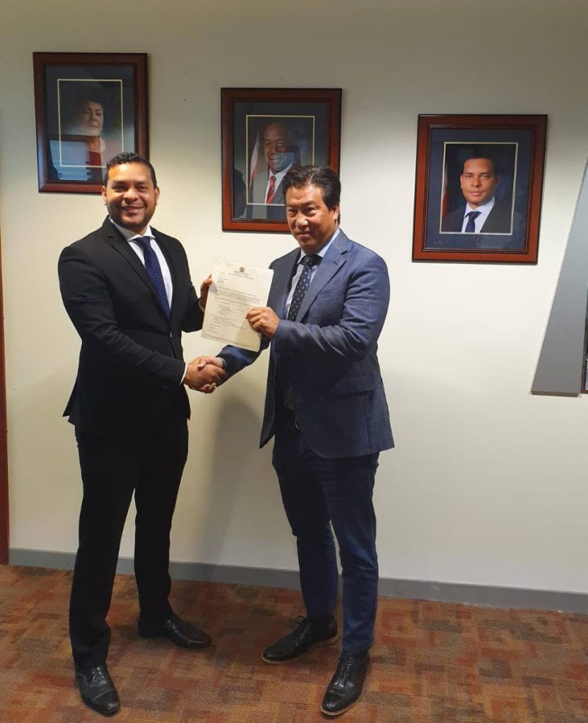 Tourism Minister Randall Mitchell (L) presnts the Instrument of Appointment to new chairman of the Trinidad  Tourism Limited Board Howard Chin Lee. 
